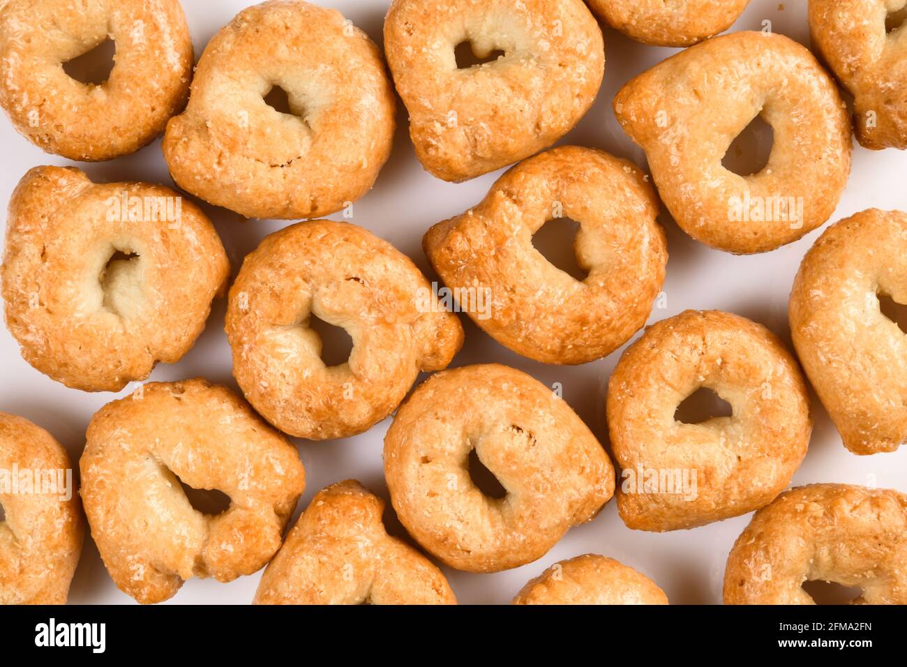 Taralli or tarallini, traditional italin snack from wheat dough. Background from some pieces closeup isolated on white. Stock Photo