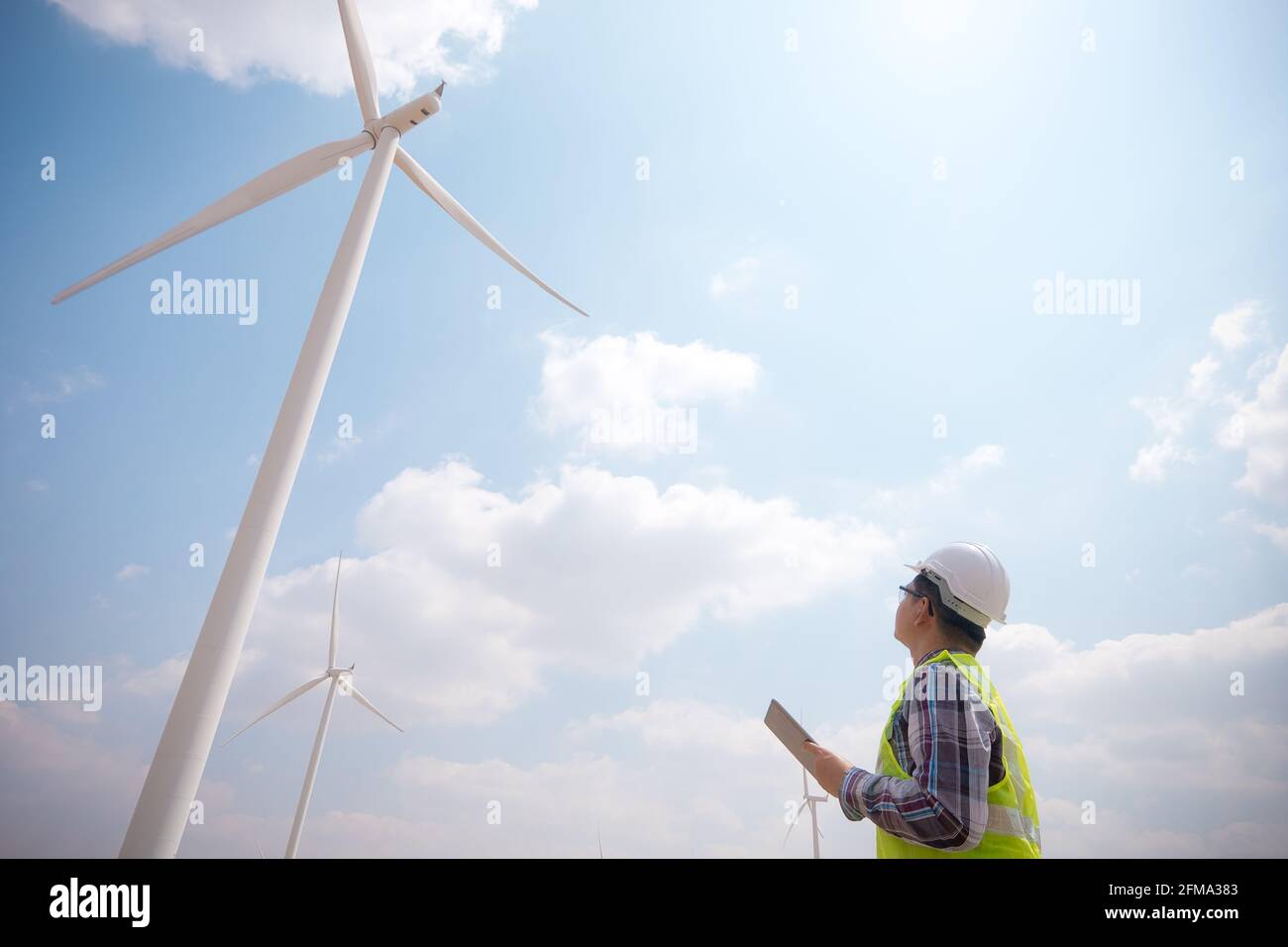 Successful engineer windmills using tablet with wind turbine in background Stock Photo