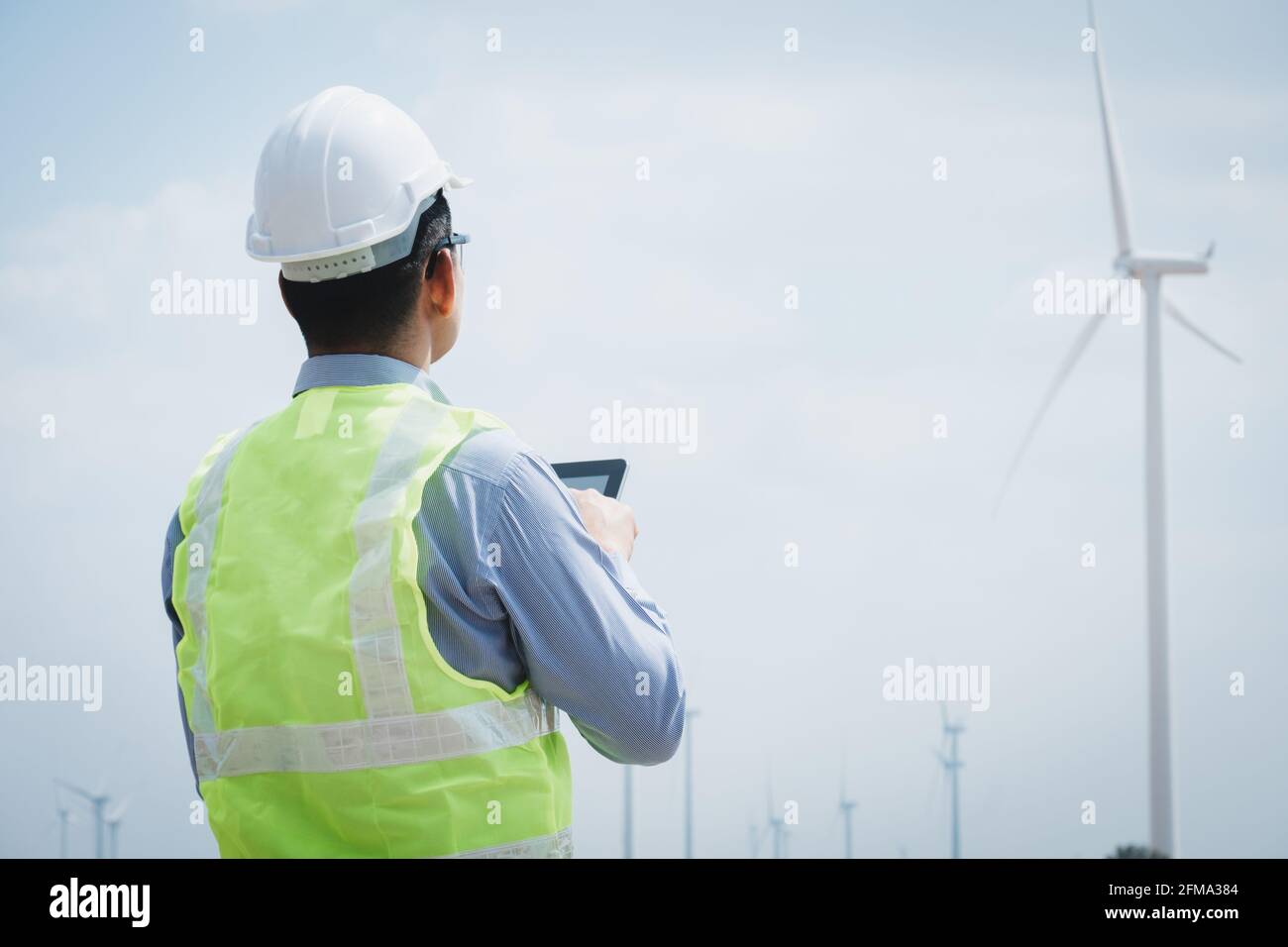Engineer windmills using tablet with wind turbine in background Stock Photo