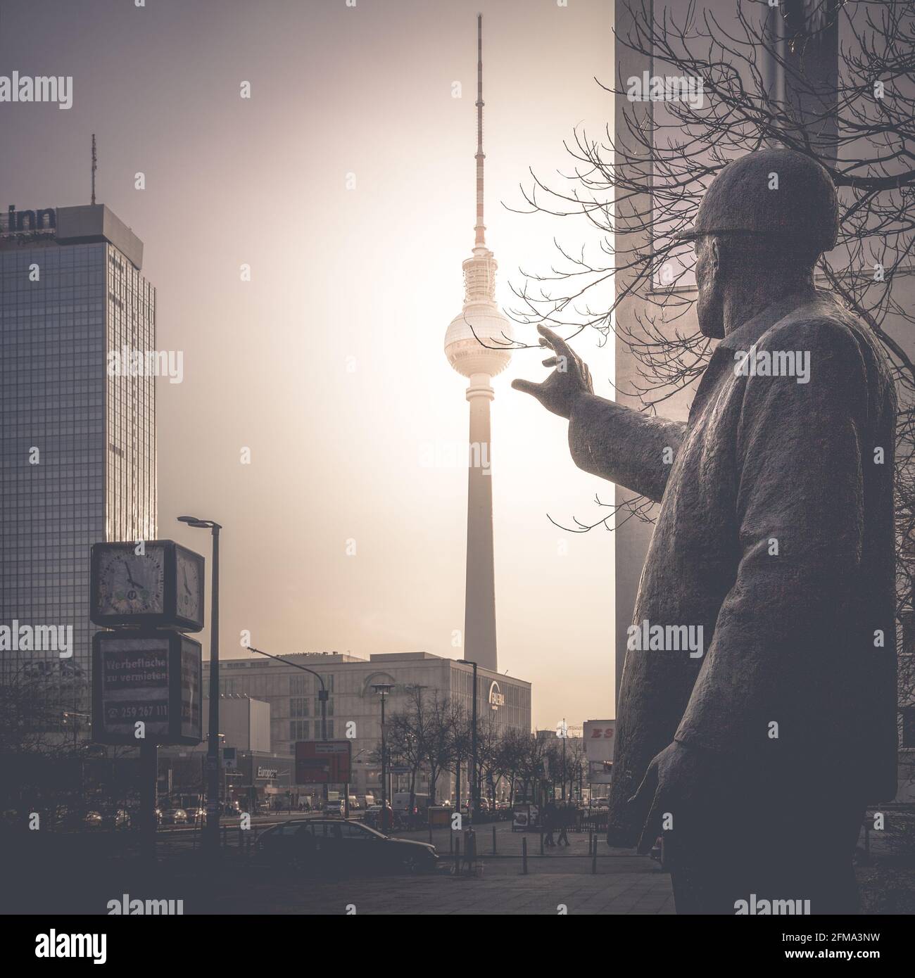 Sunset behind the television tower on Berlin's Alexanderplatz with a historical statue in the foreground. Stock Photo