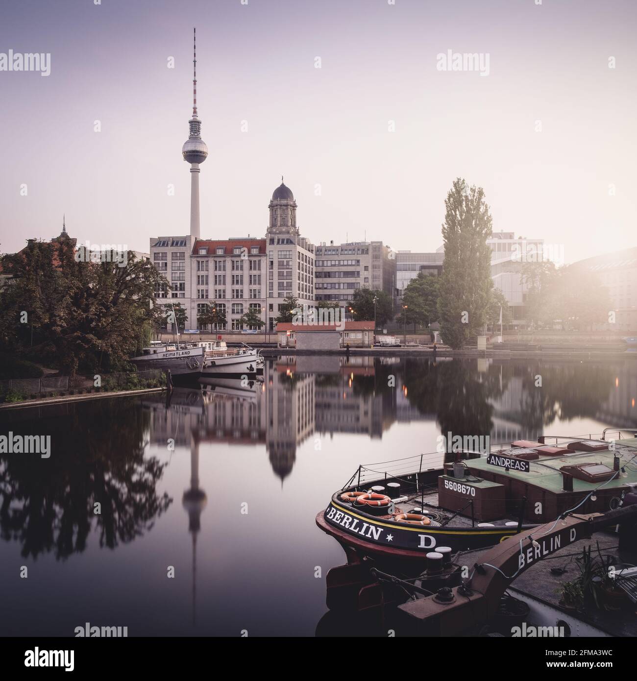 Reflection on the Spree at sunrise at the historic harbor with TV tower and old town house in Berlin. Stock Photo