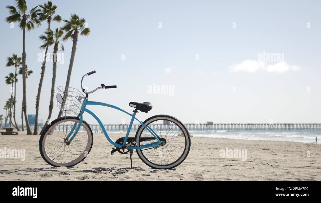 Blue bicycle, cruiser bike by sandy ocean beach, pacific coast, Oceanside  pier California USA. Summertime vacations, sea shore. Vintage cycle, palms,  sky, lifeguard tower watchtower hut, car truck Stock Photo - Alamy