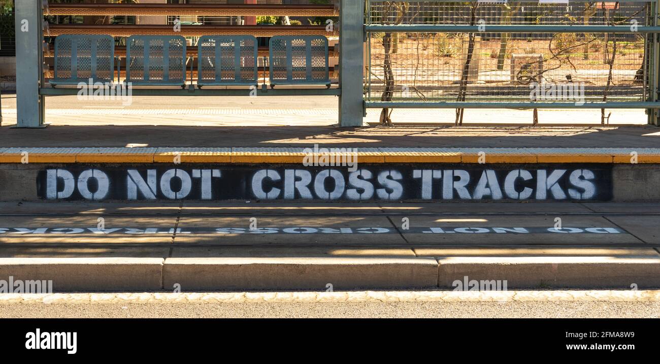 do not cross tracks painted on the tracks and curb at a light rail station Stock Photo