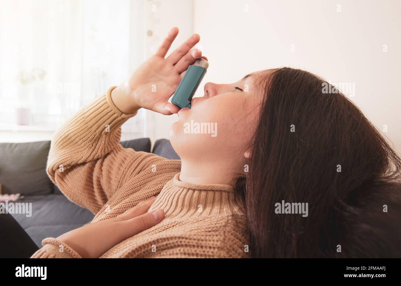 Pretty Inhaler Pretty young brunette woman using an asthma inhaler during strong ...