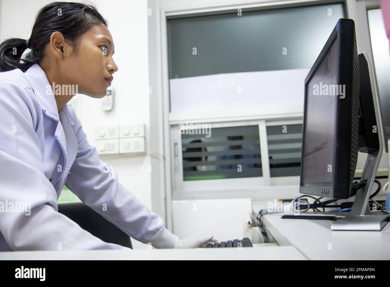 Medical staff checks registration on computer display. Night shifts works with the electronic card index at hospital. Stock Photo