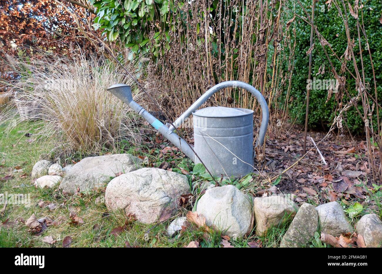 Old watering can in the flowerbed, nostalgic mood Stock Photo