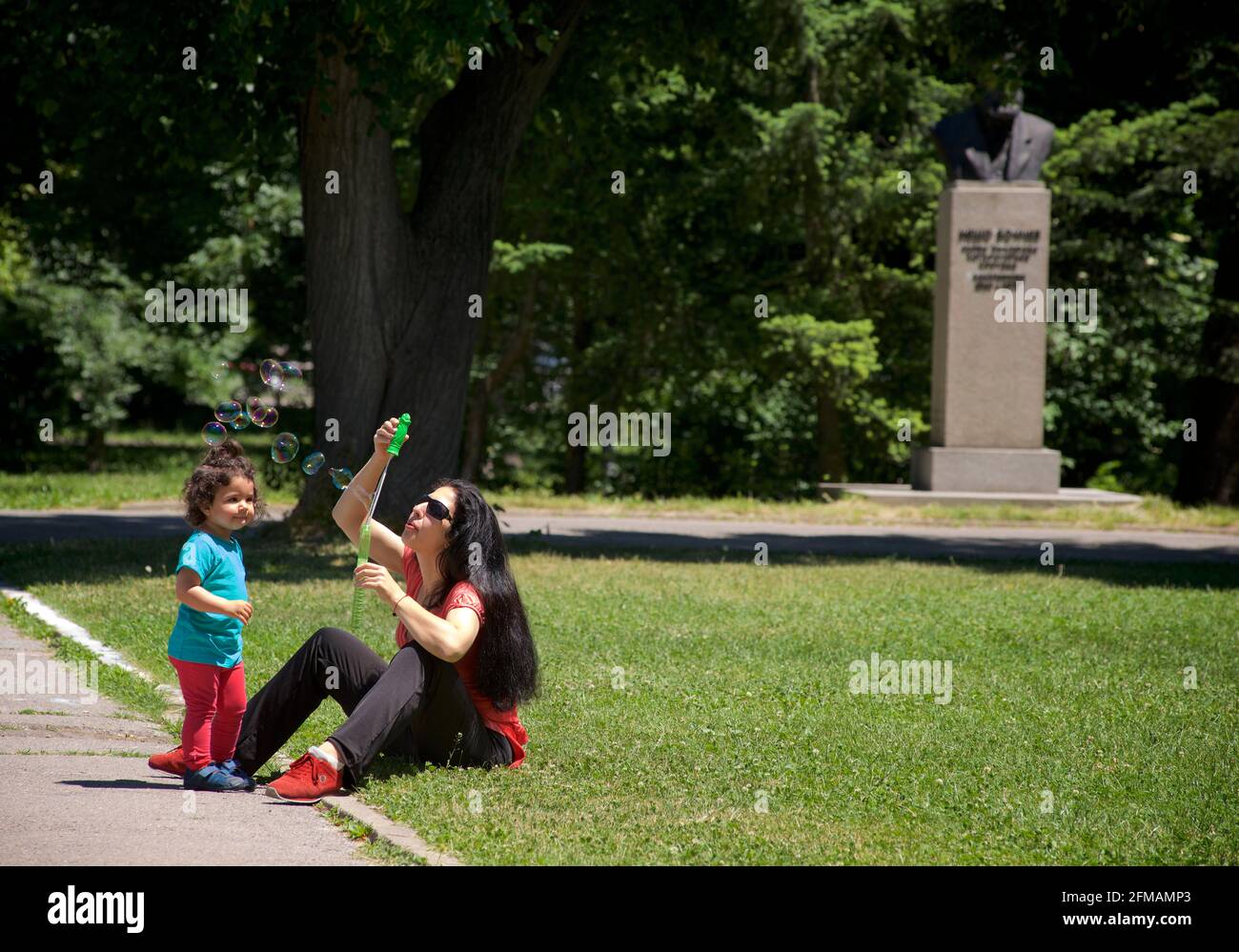 Bulgarian mother with child, making bubbles. Borisova gradina or Knyaz-Borisova gradina park, Sofia, Bulgaria. Stock Photo