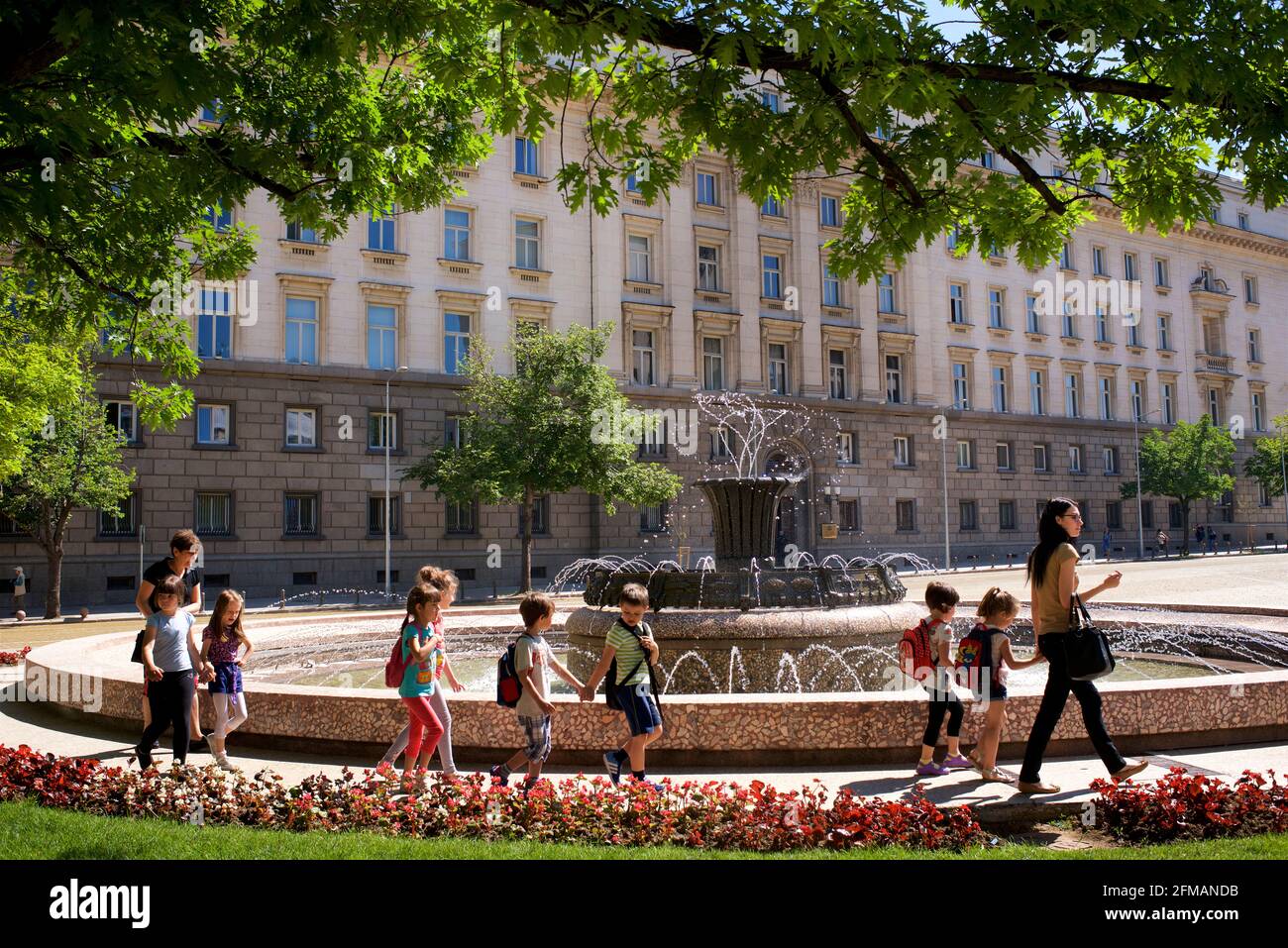 Bulgarian schoolchildren waking past a fountain in Atanas-Burov Plaza,  besides the Presidential Palace  in Sofia, Bulgaria Stock Photo