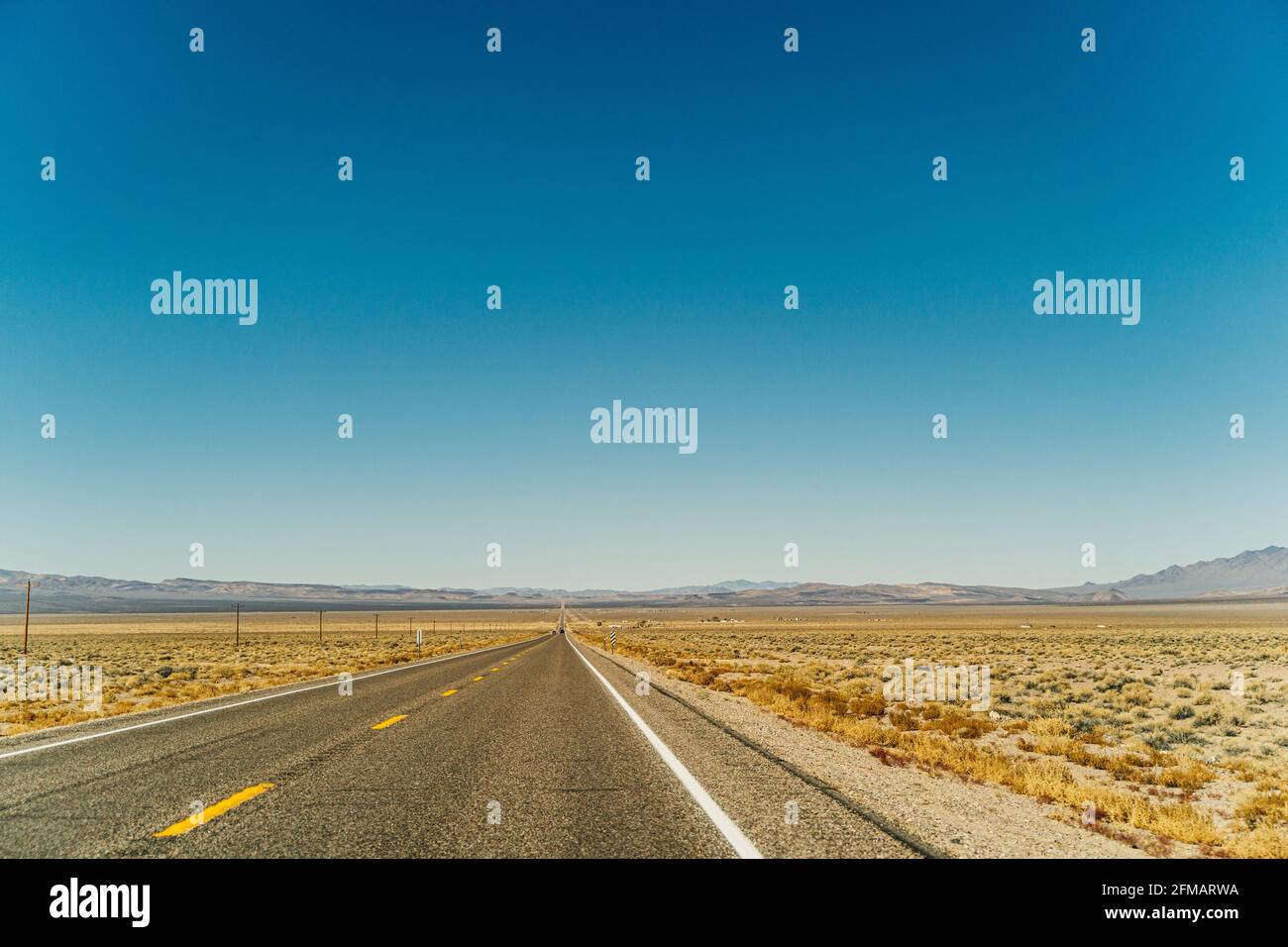 Desert highway road leading to the horizon against clear blue sky and ...
