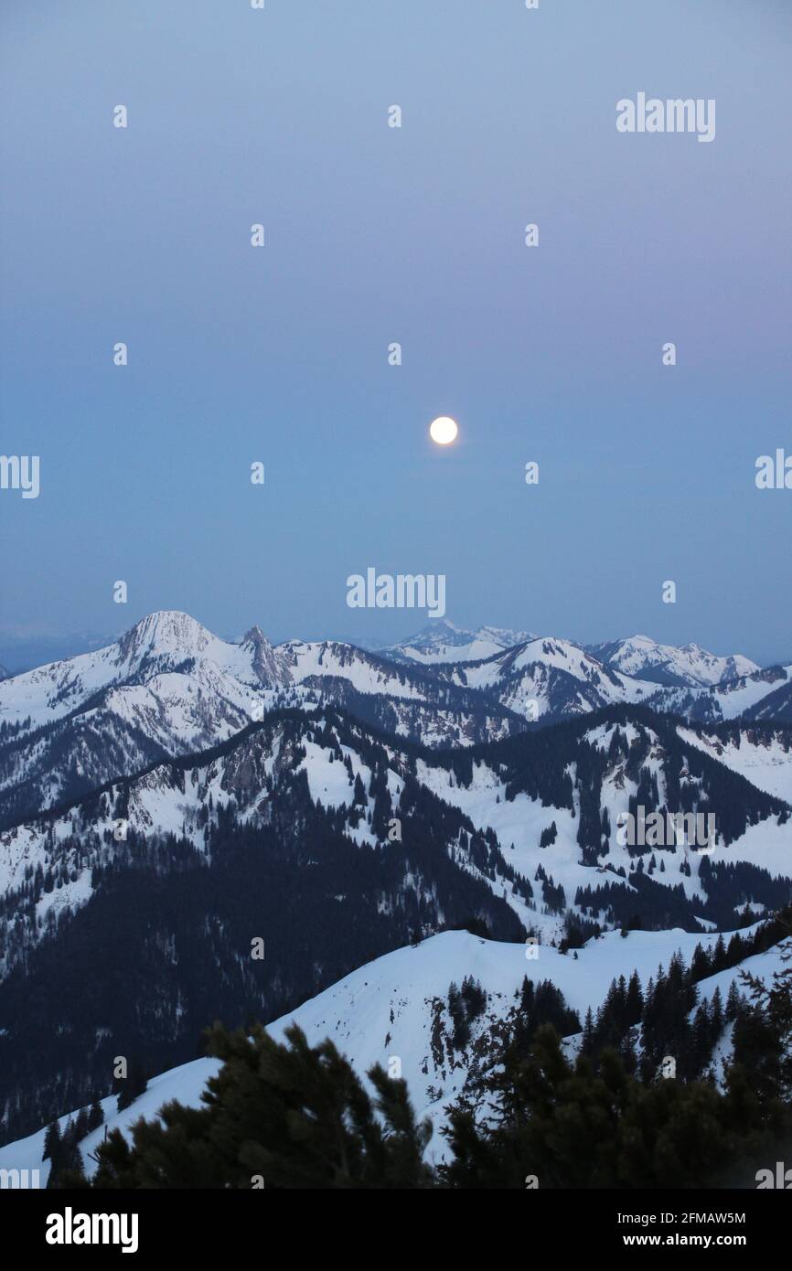 From the Auerspitze to the north, the setting moon over the mountains from left to right Risserkogel (1825m), Blankenstein (1768m), Bendiktenwand (1799m), Setzberg, Hirschberg, Wallberg, shortly before sunrise. Europe, Germany, Bavaria, Upper Bavaria, Bavarian Alps, Mangfall Mountains, Spitzingsee Stock Photo