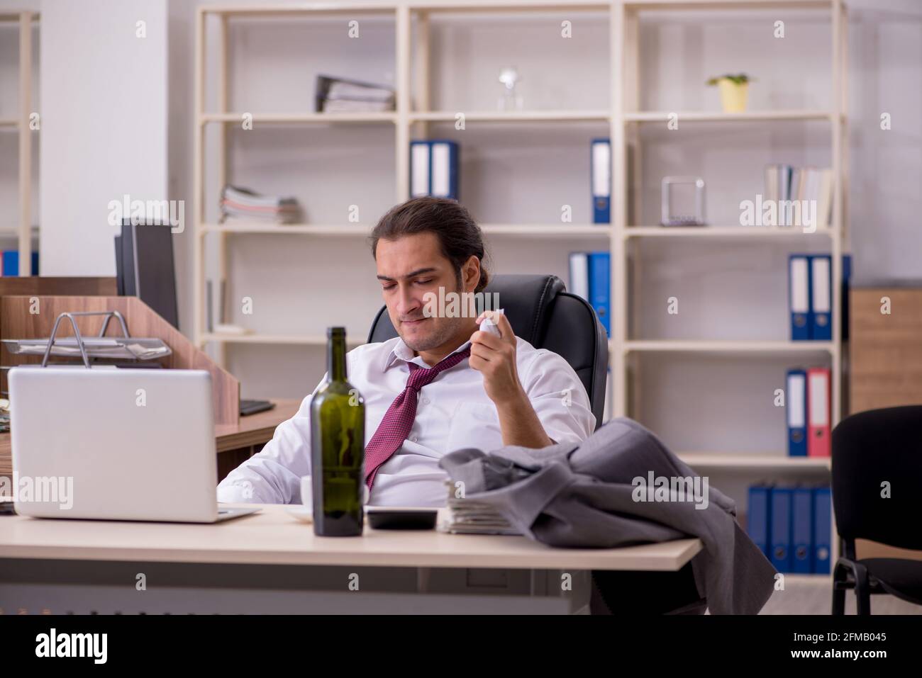 Young employee drinking alcohol in the office Stock Photo - Alamy