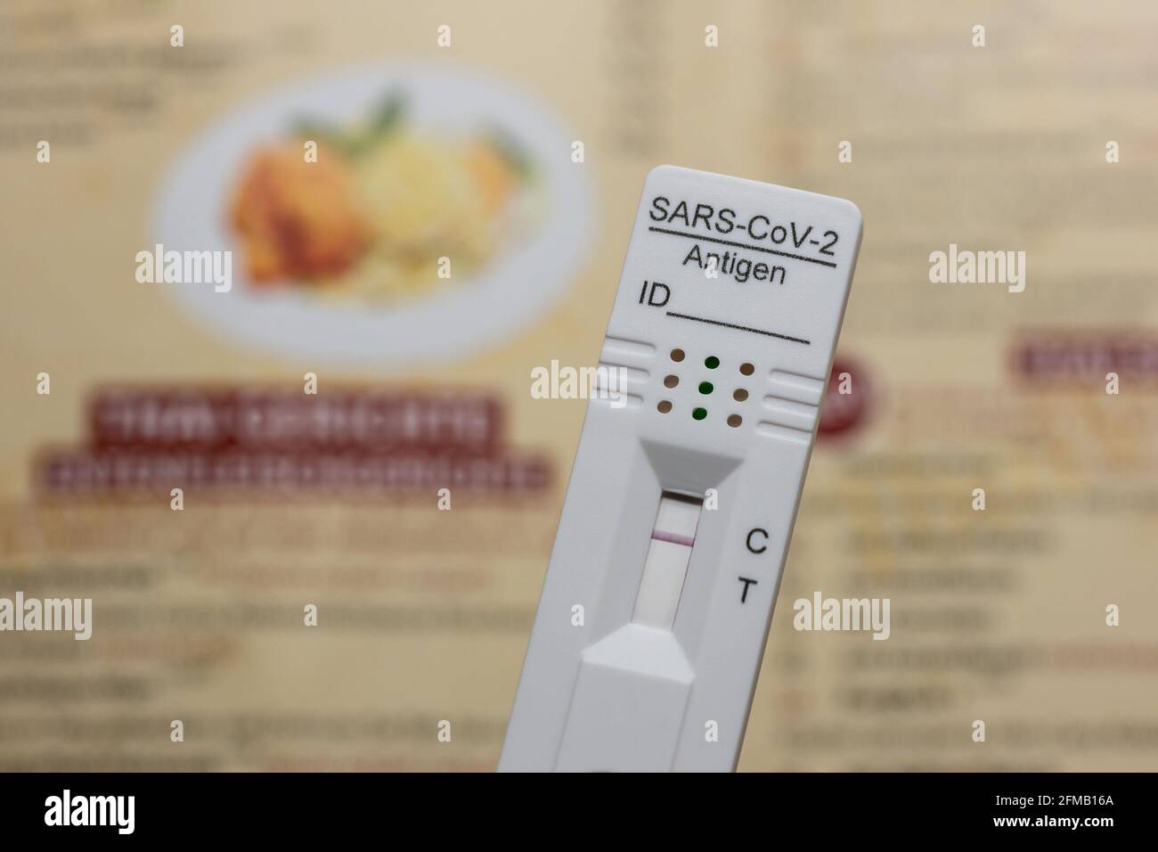 Testing Before Going To A Restaurant: Rapid Antigen Corona Test Showing A Negative Result In Front of A Menu, Berlin, Germany Stock Photo