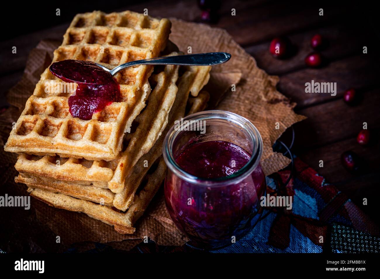 Waffles stacked on cooling racks with a dollop of homemade cranberry jam, mason jar, spoon, moody mood Stock Photo