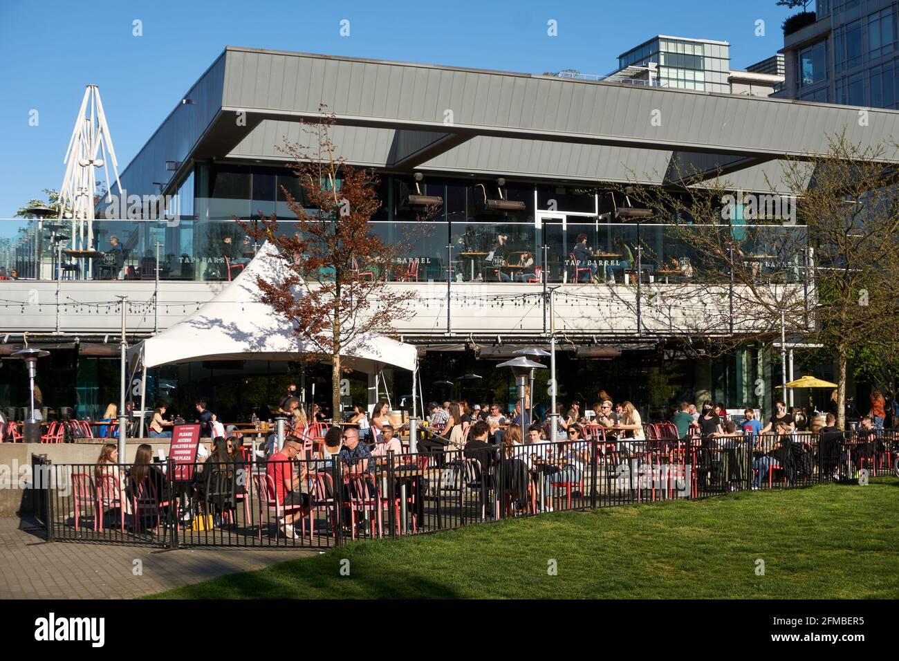 Crowded waterfront outdoor patio of Tap and Barrel restaurant during the COVID-19 pandemic, Olympic Village on False Creek, Vancouver, BC, Canada Stock Photo