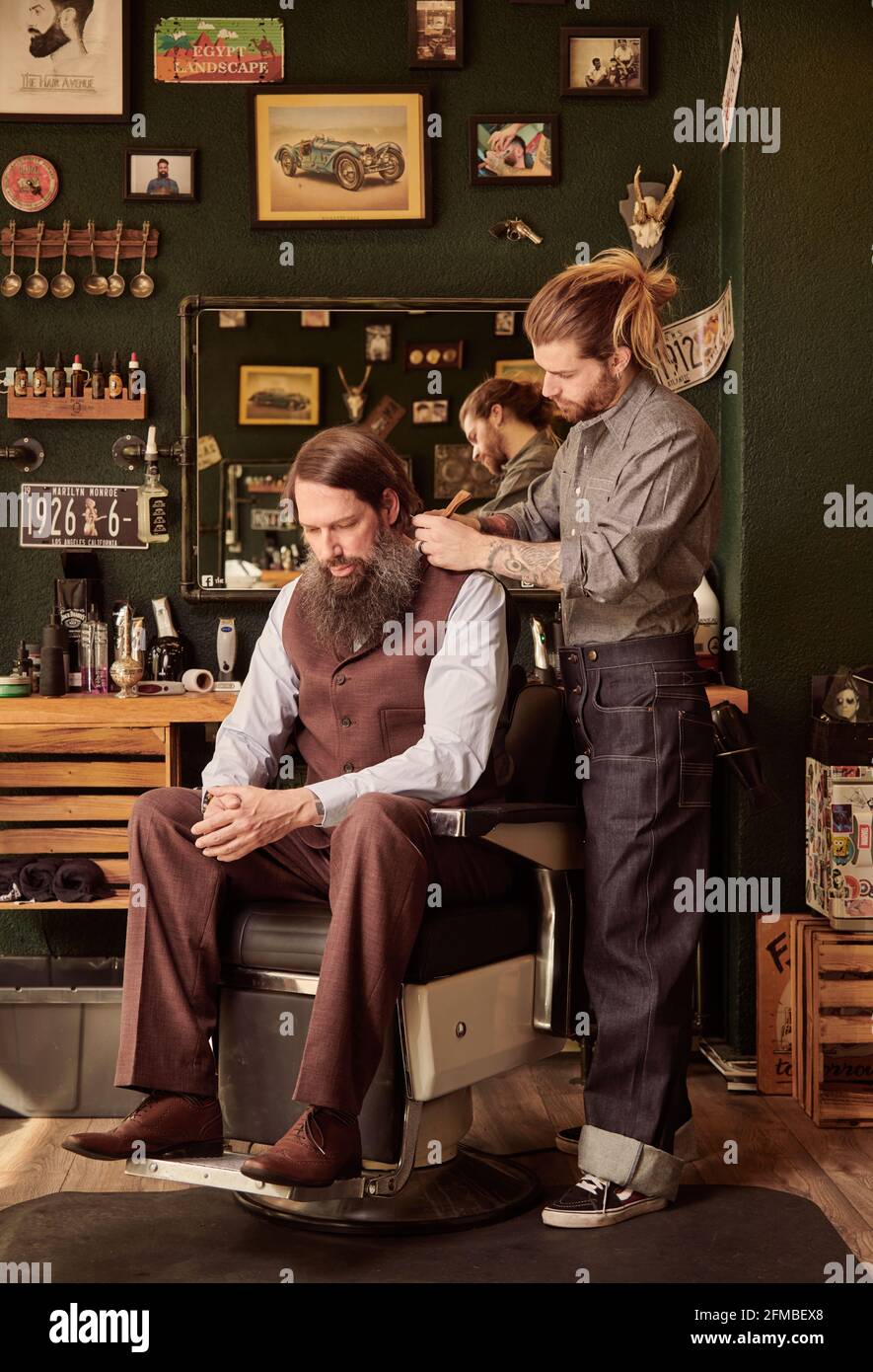 Young man coiffures bearded man in barbershop Stock Photo