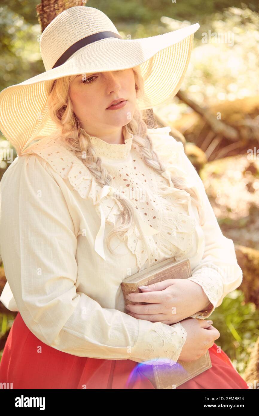 Young blonde woman in nostalgic clothes with book Stock Photo