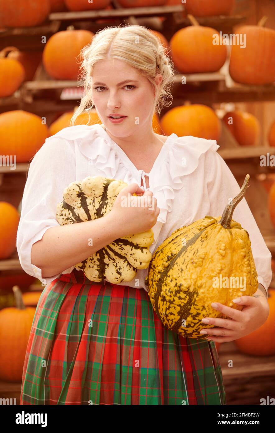 Young woman in plaid skirt with pumpkins Stock Photo