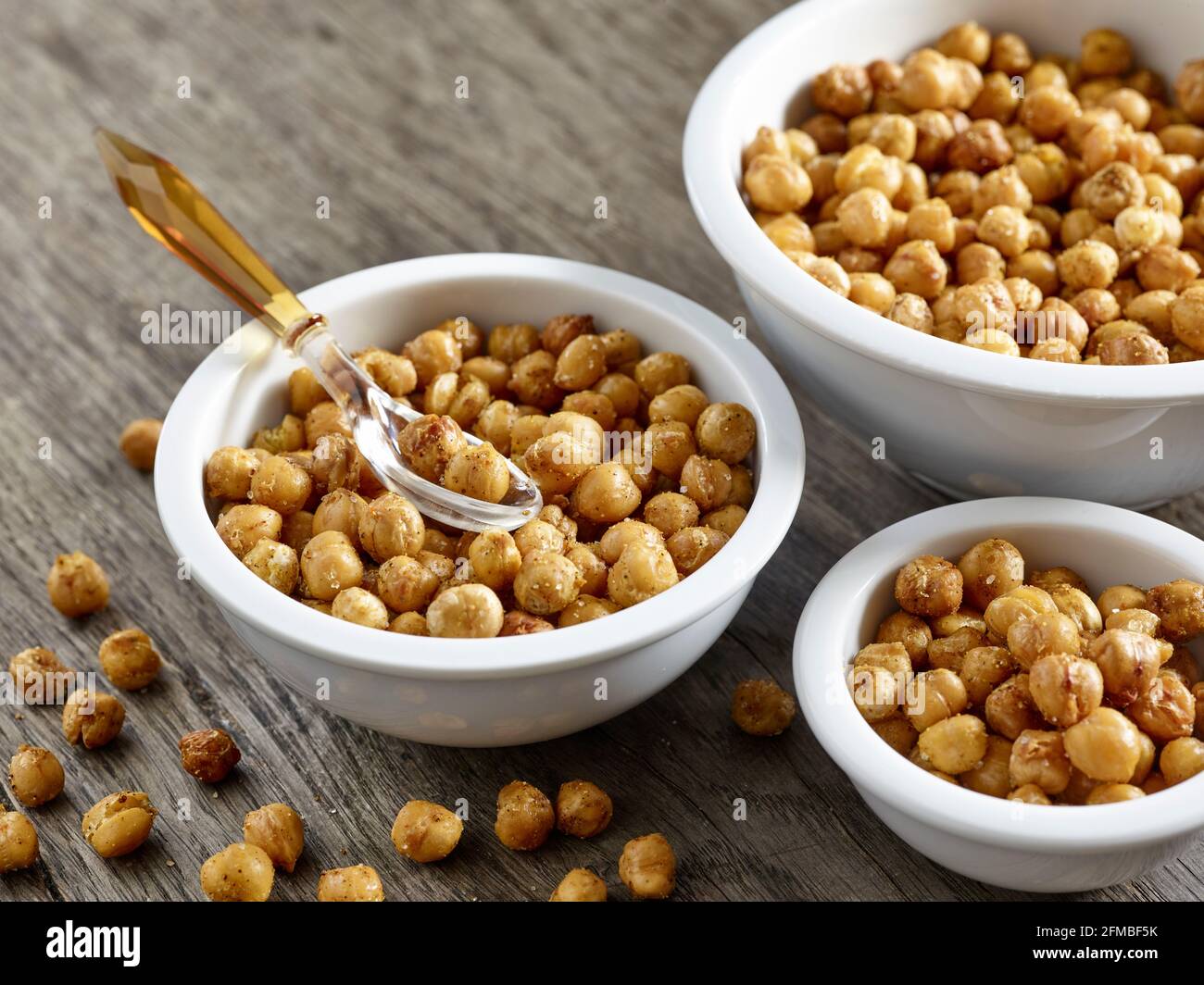 Ayurvedic cuisine - Oven-roasted chickpeas in porcelain bowls of various sizes on a wooden plate Stock Photo
