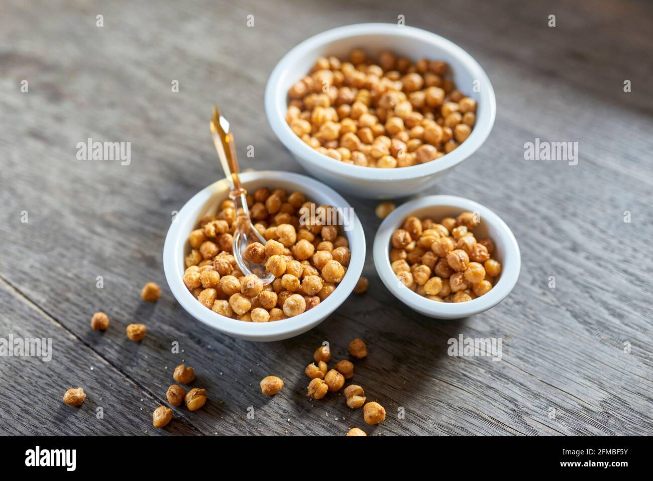 Ayurvedic cuisine - Oven-roasted chickpeas in porcelain bowls of various sizes on a wooden plate Stock Photo