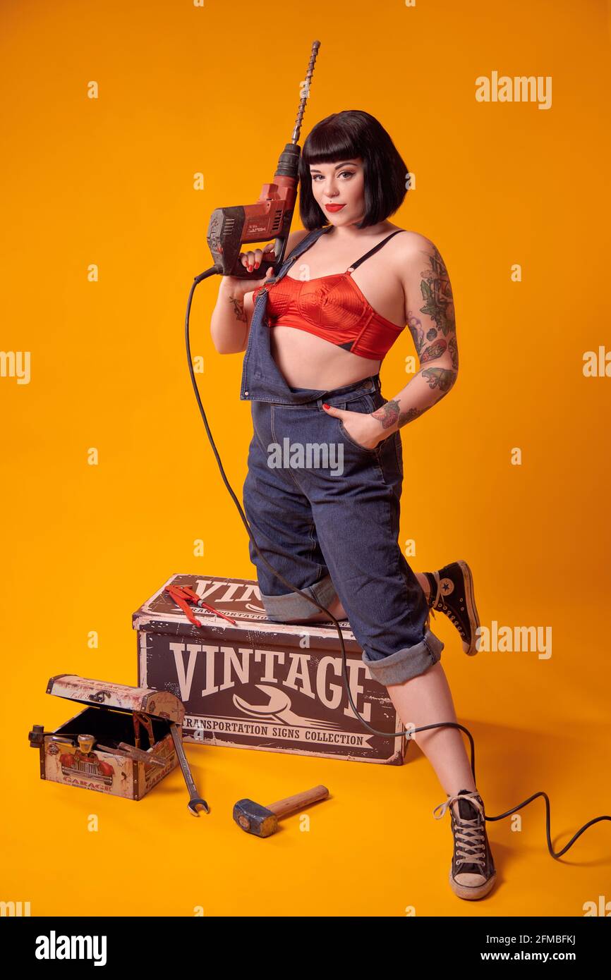 Tattooed curvy model with black hair in pin-up style as a mechanic Stock Photo