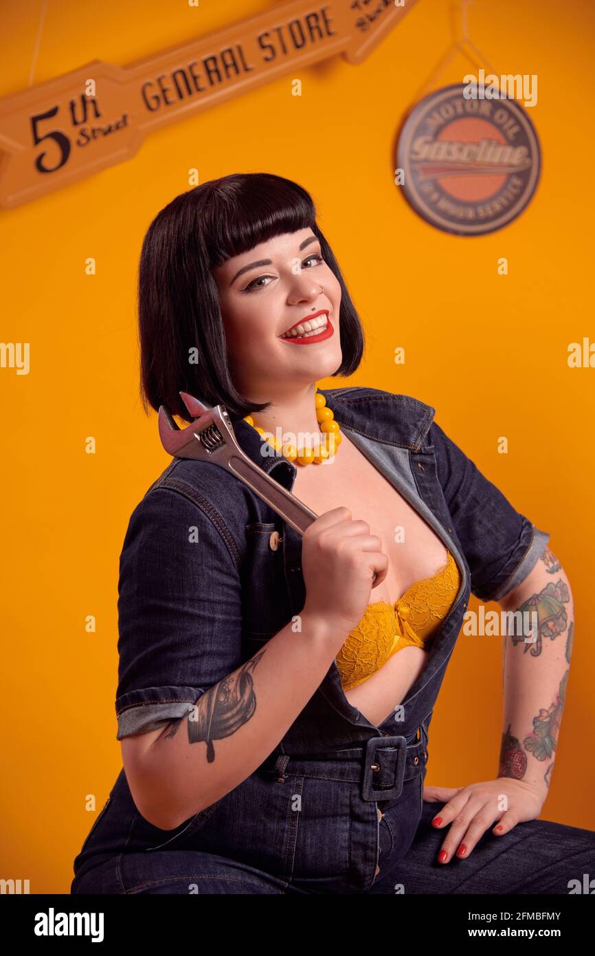 Tattooed curvy model with black hair in pin-up style as a mechanic Stock Photo