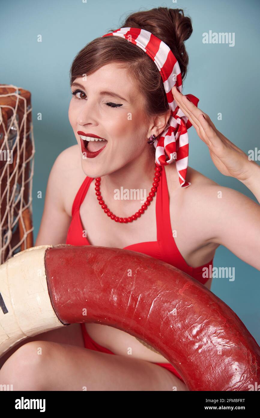 Brunette model in maritime pin-up style makes the sailor's greeting Stock Photo