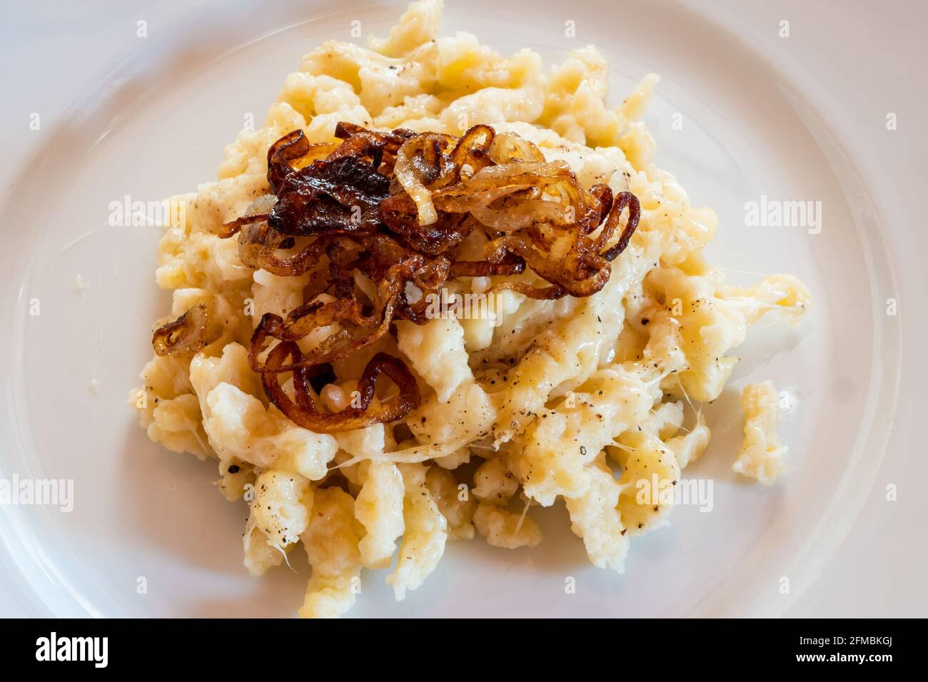 Tyrolean Chees Noodles or Pasta called Kaesespaetzle with Fried Onion on a White Plate, a Typical and Traditional Austrian Dish Stock Photo