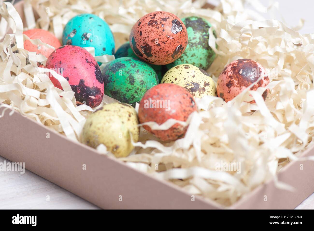 colored quail eggs in a basket lie Stock Photo
