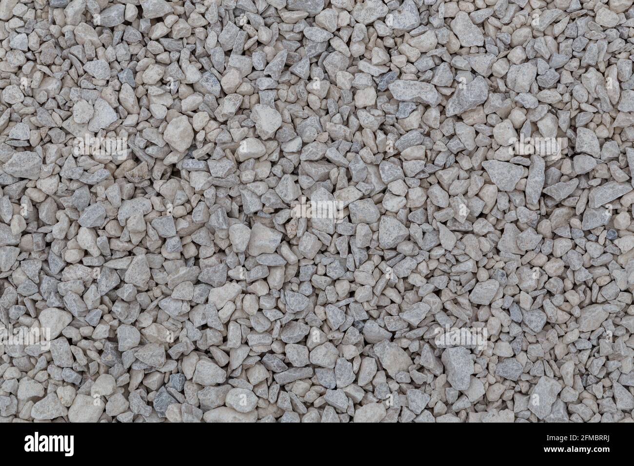 Dry white limestone ballast flat full frame background. Small gray dusty broken macadam stones texture. Viiew from above. Stock Photo