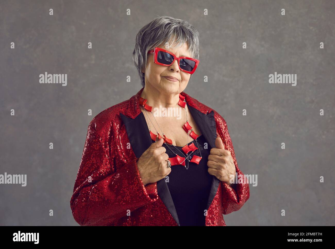 Headshot portrait of fashionable senior woman on grey studio background Stock Photo