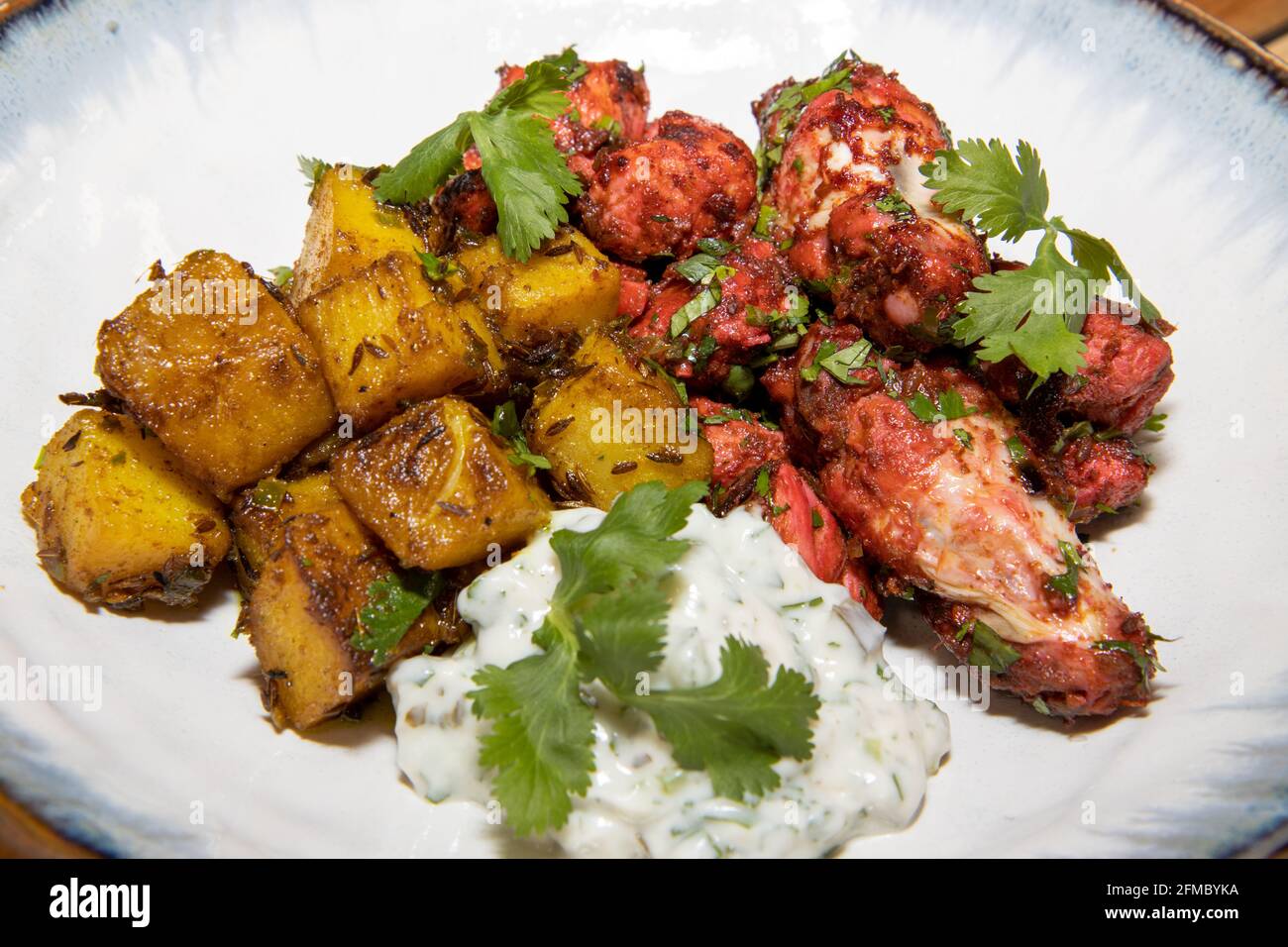 A plate of delicious Tandoori Chicken and cumin pan roasted potatoes Stock Photo