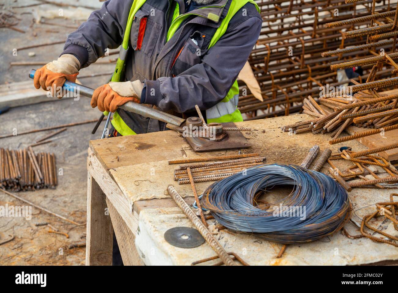 Construction worker bending rebar using manual bending machine at a