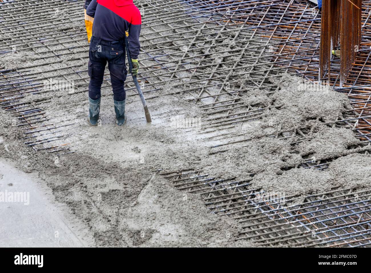 Construction worker using concrete vibrator for compacting concrete to eliminate voids and
