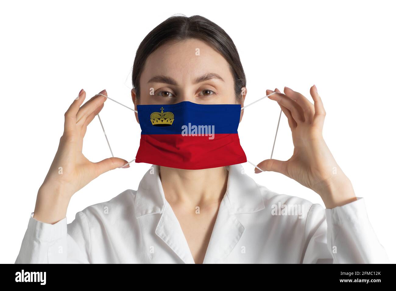 Respirator with flag of Liechtenstein Doctor puts on medical face mask isolated on white background. Stock Photo