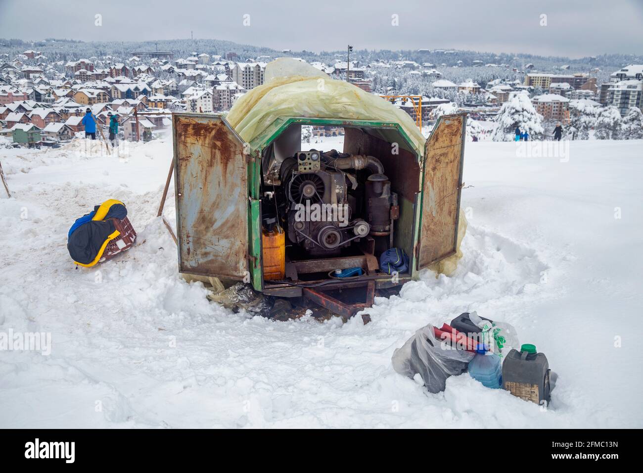 Homemade rope tow ski lift with teenage skiers in background at