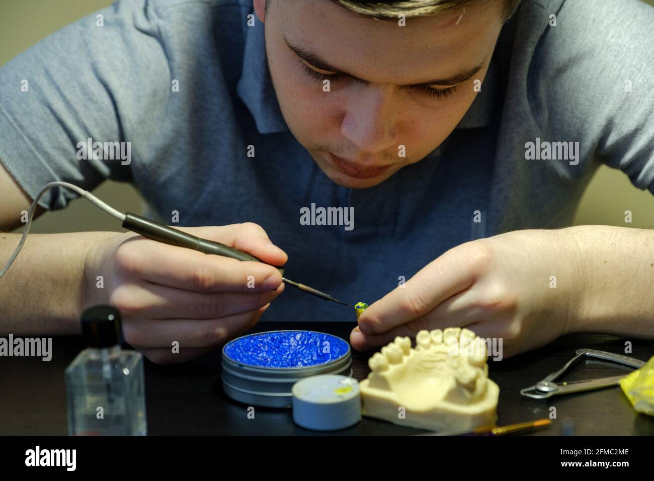 Dental technician modelling tooth crowns with hot wax. Workplace of a