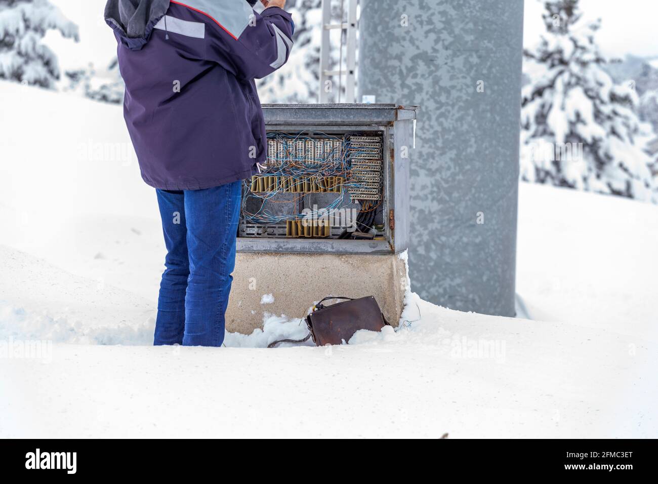 Wiring telephone connection box, technician standing in the snow and repair telephone line. Stock Photo