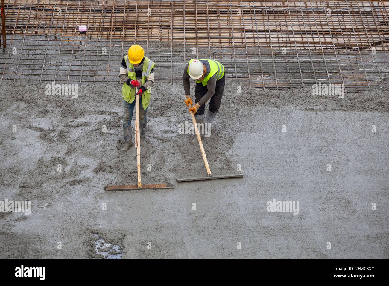 Workers in rubber boots stands in concrete and leveling, spreading