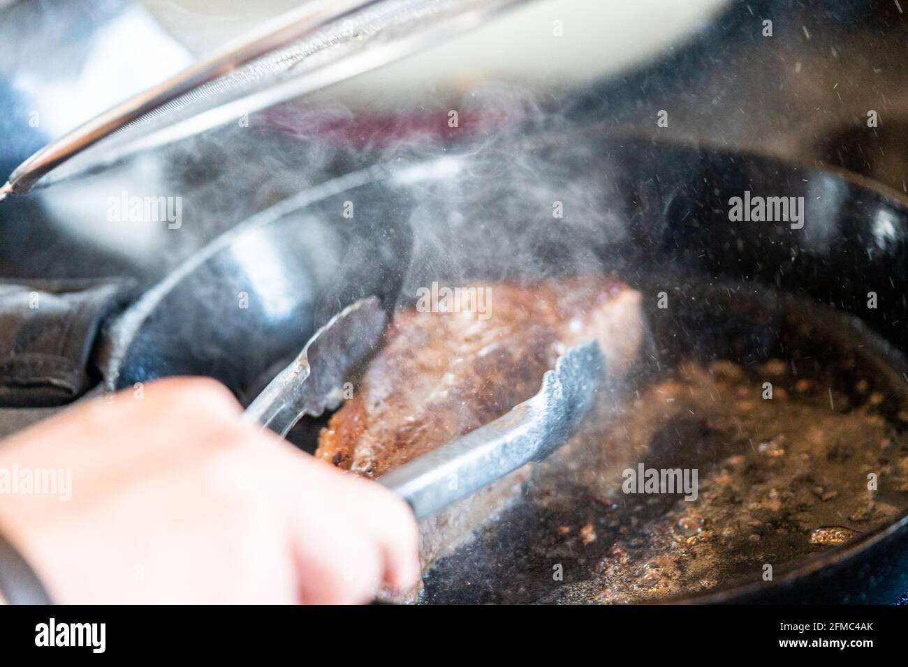Frying New York strip steak in cast iron frying pan over the electric stove Stock Photo Alamy