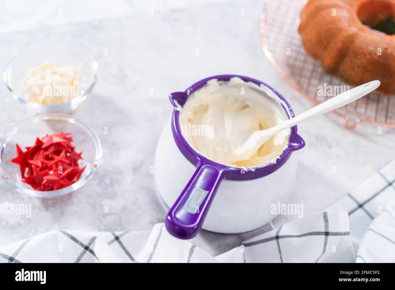 Melting storebought buttercream frosting in candy melting pot to glaze bundt cake Stock Photo