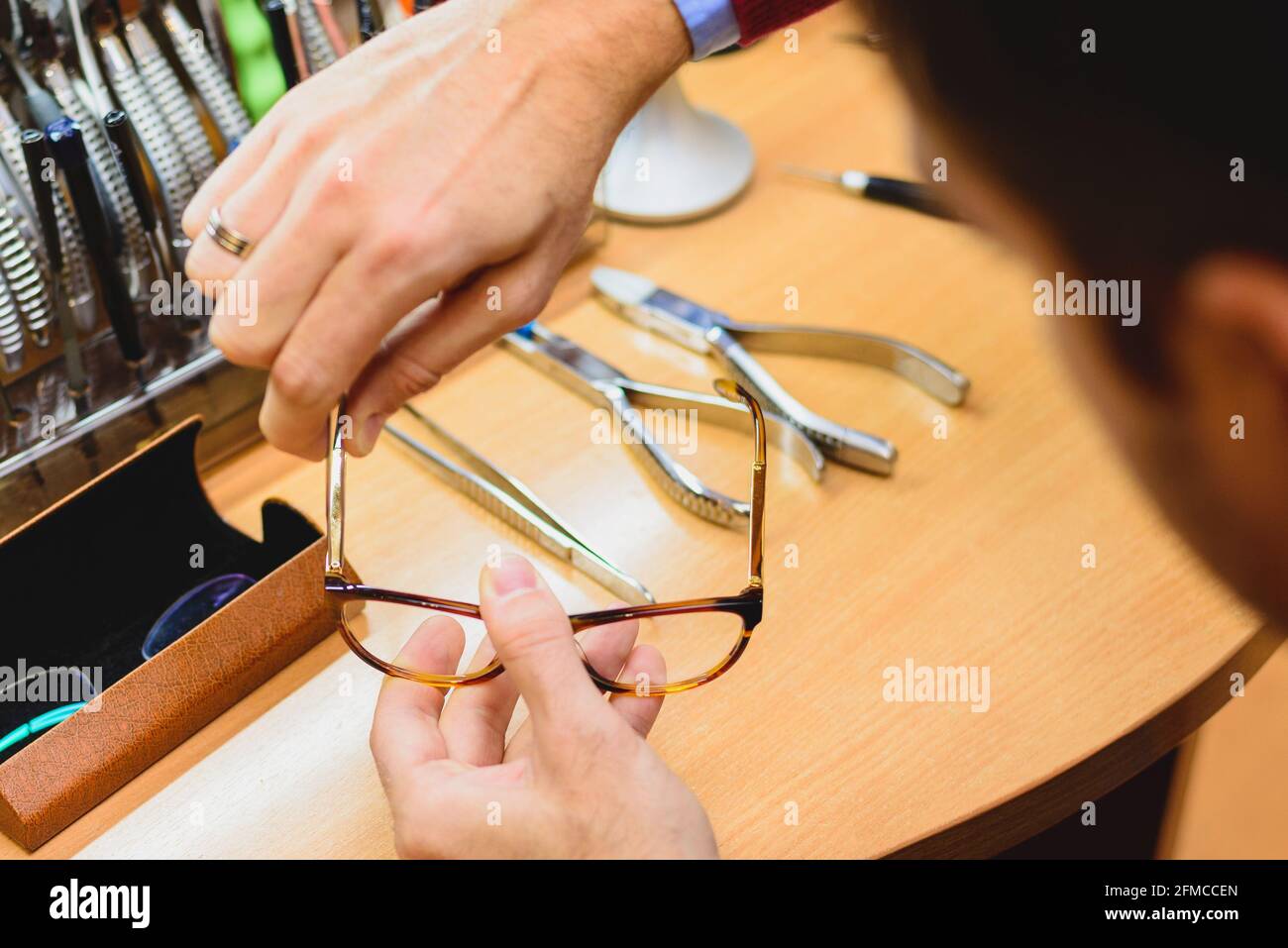 Closeup of male optician's / optometrist's hands repairing eyeglasses Stock Photo