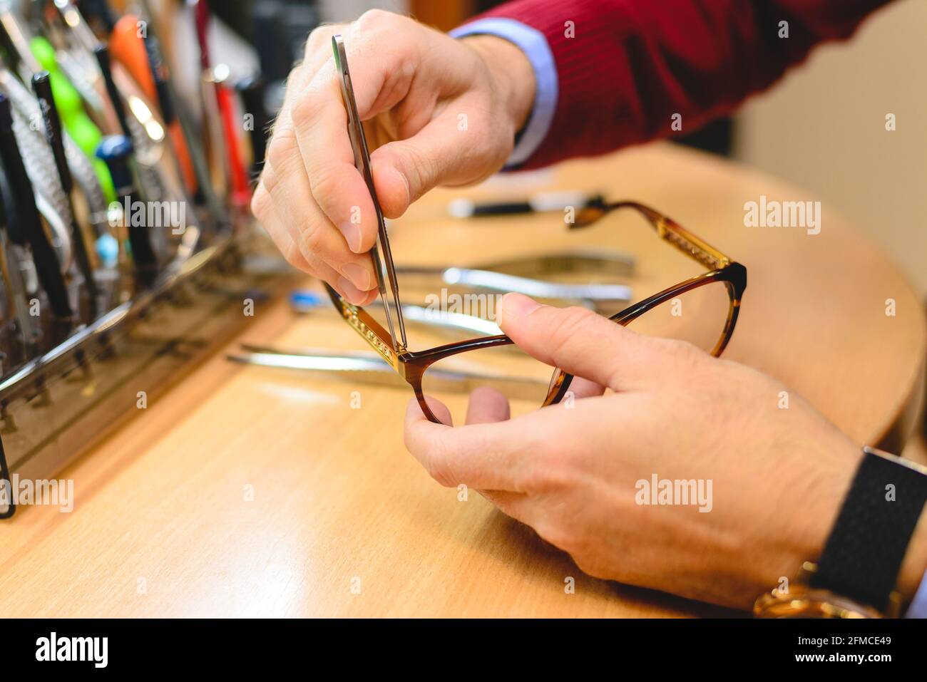 Closeup of male optometrist / optician's hands repairing eyeglasses Stock Photo
