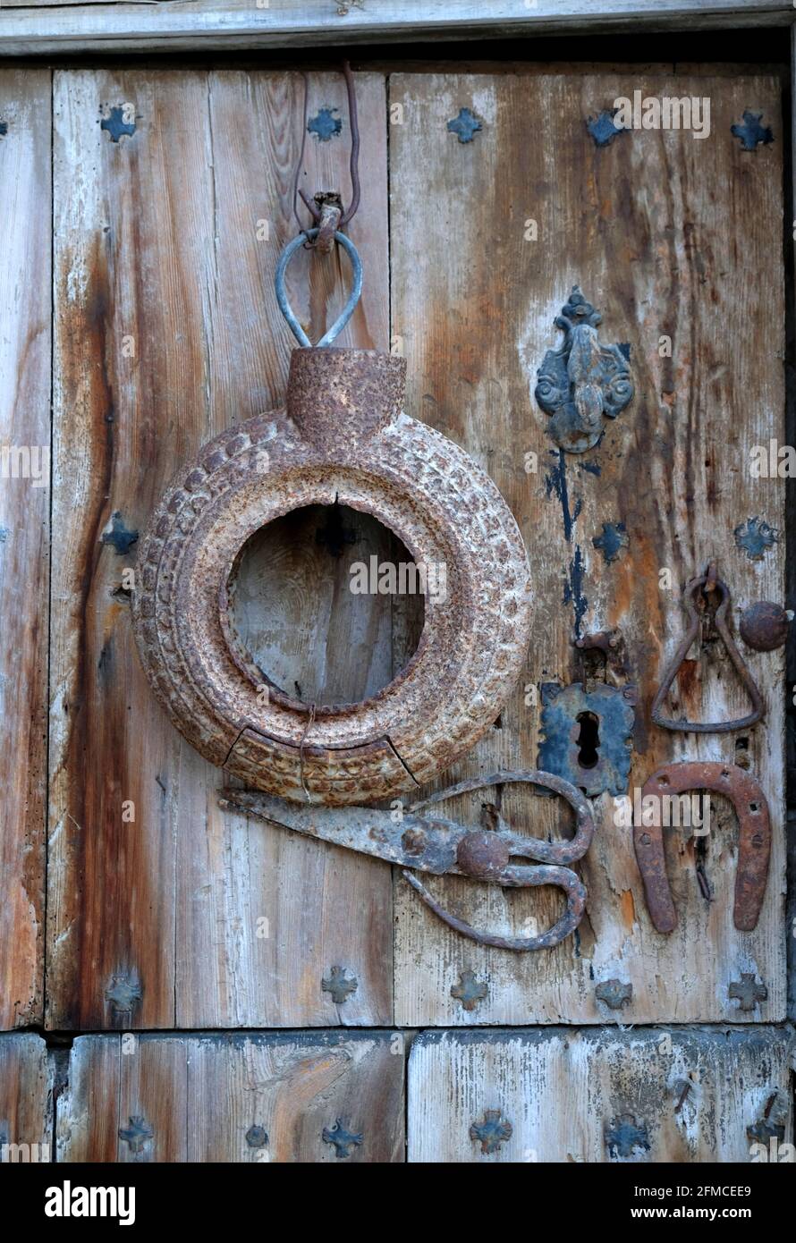 An old and delapidated back door in the village of Torrebaja in Valancia, Spain. It is decorated with an iron knocker and a pair of old sheep shears Stock Photo