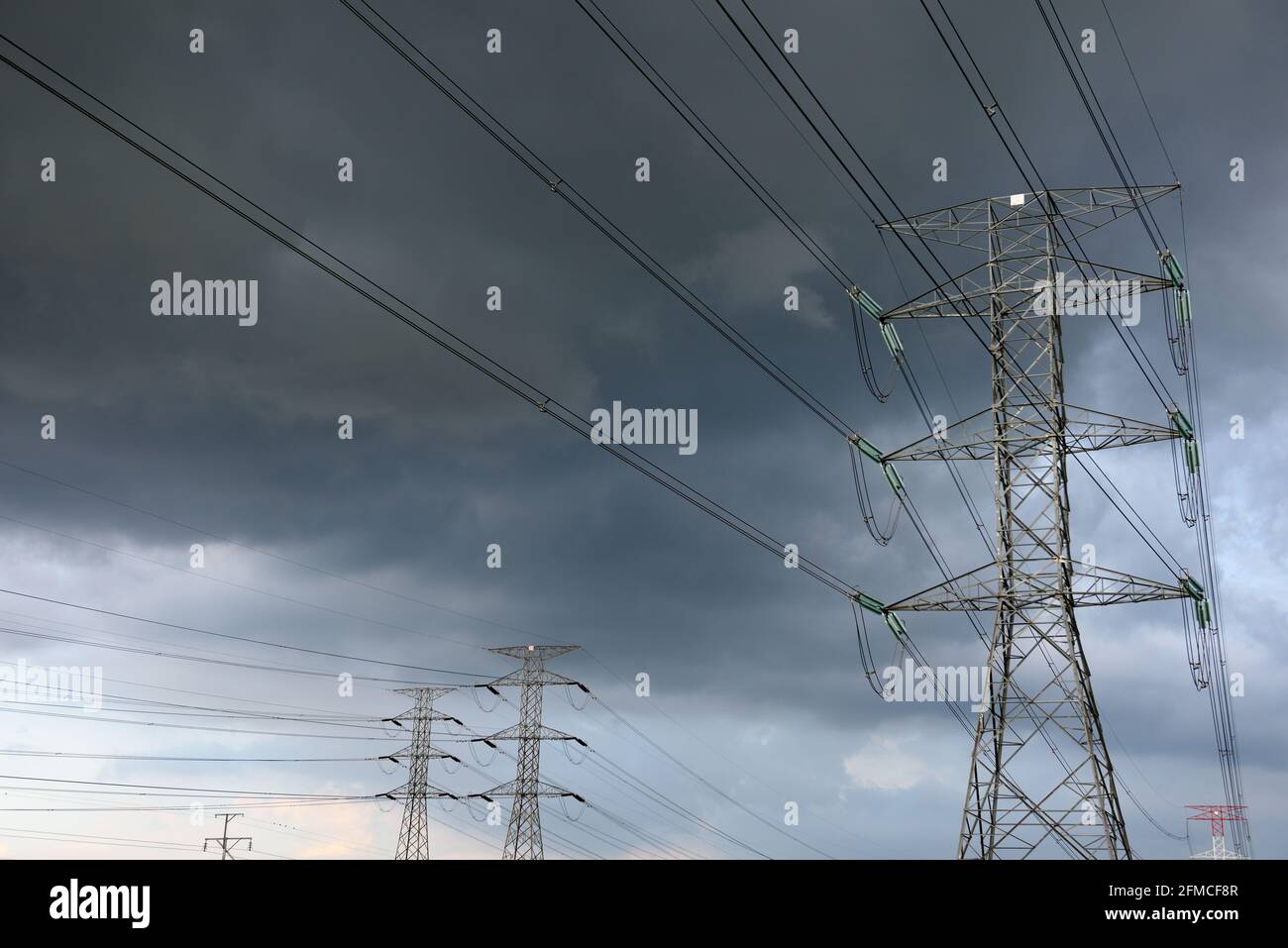 Several high voltage electrical grid transmission towers underneath a stormy sky near Kuala Lumpur, Malaysia Stock Photo