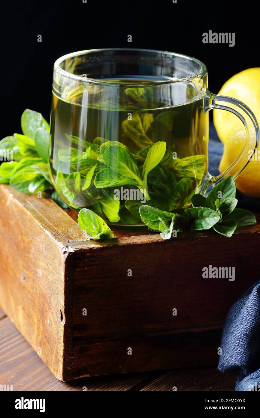 Mint herbal tea in a glass cup on dark moody wooden rustic background with blue linen napkin, closeup, copy space, natural medicine, naturopathy, drin Stock Photo