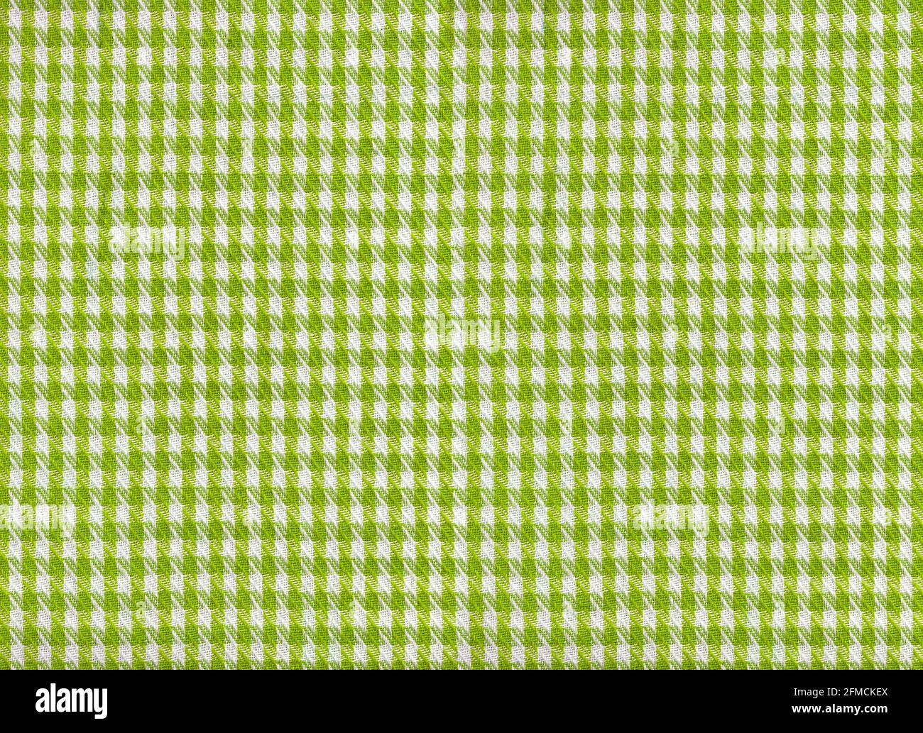 A flat area of woven fabric as a background texture and pattern green and white gingham Stock Photo