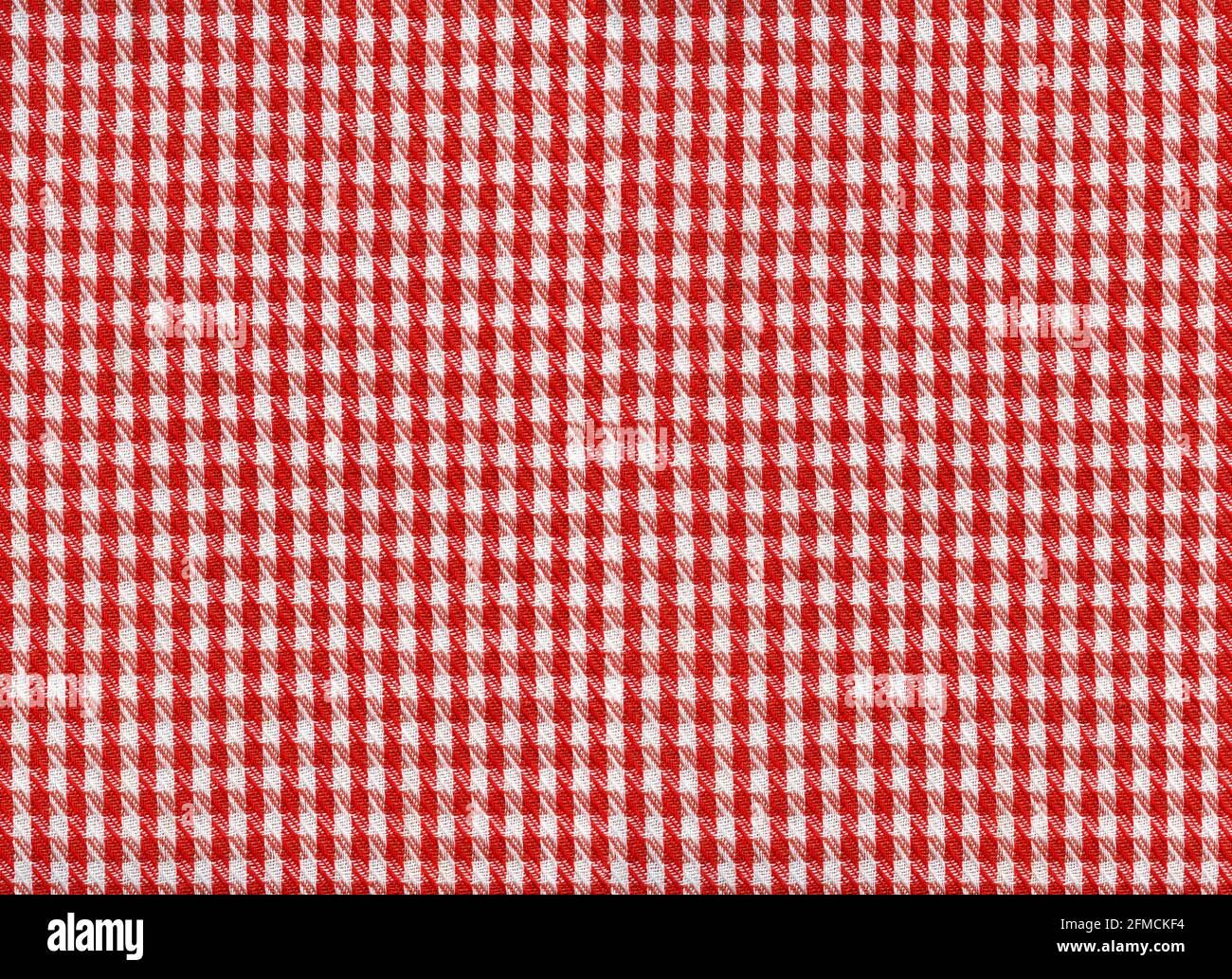 A flat area of woven fabric as a background texture and pattern red and white gingham Stock Photo