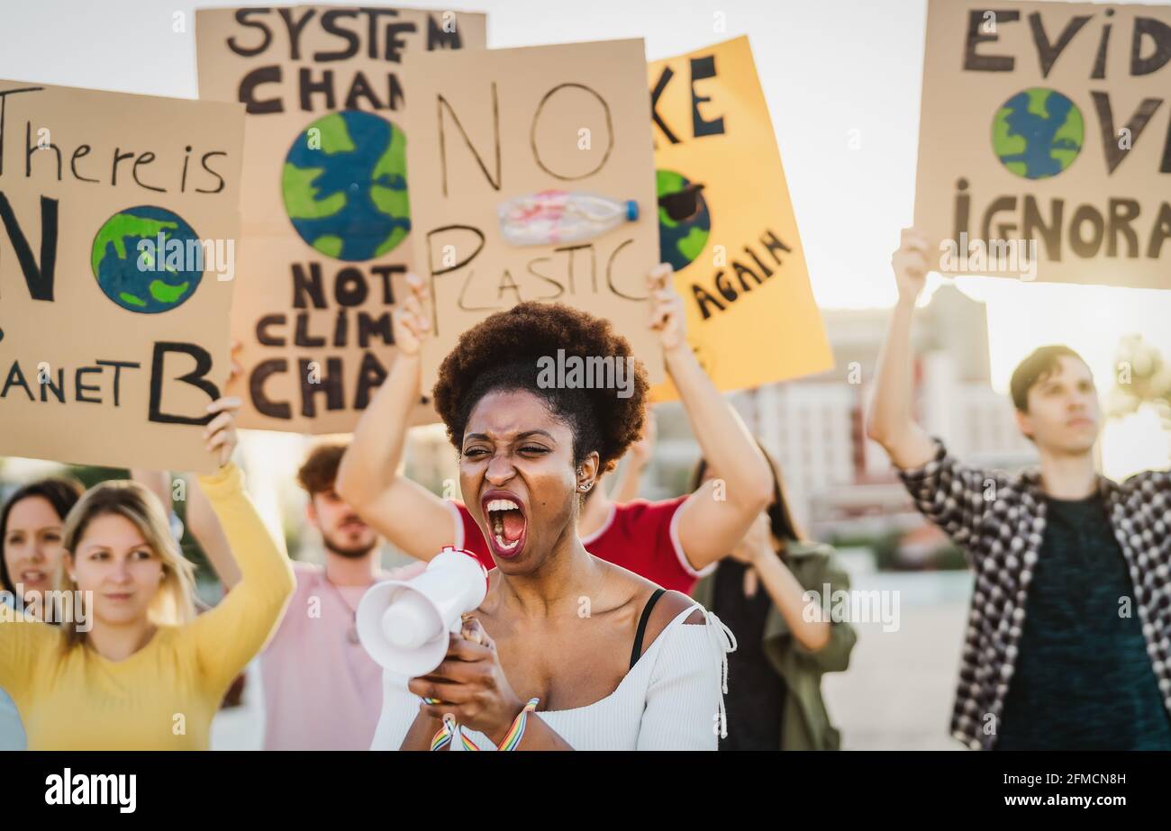 Demonstrators group protesting against plastic pollution and climate change - Multiracial people fighting on road holding banners Stock Photo