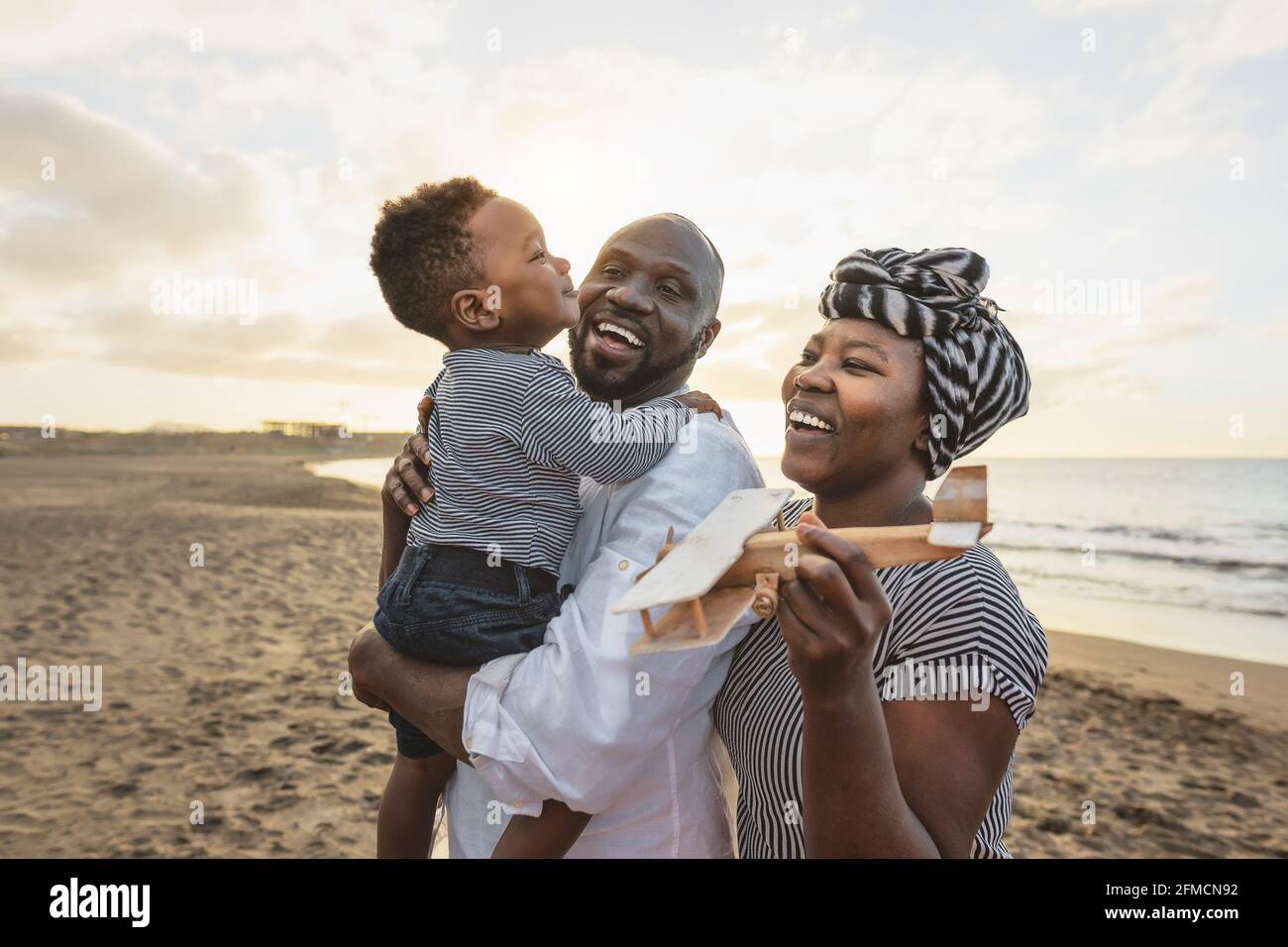 Happy African family having fun on the beach during summer vacation - Parents love and unity concept Stock Photo