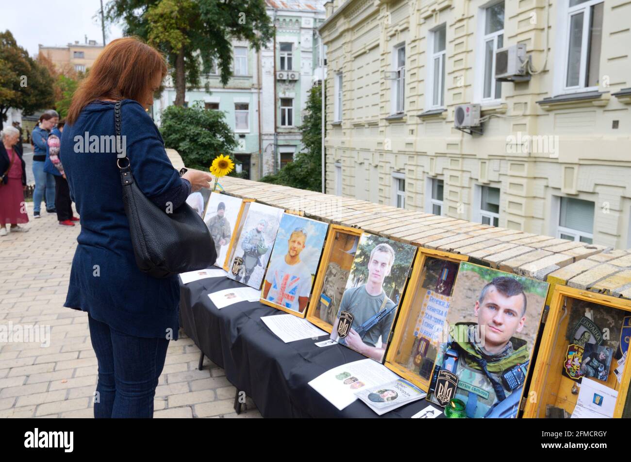 Woman standing in front of the Wall of Remembrance with portraits of